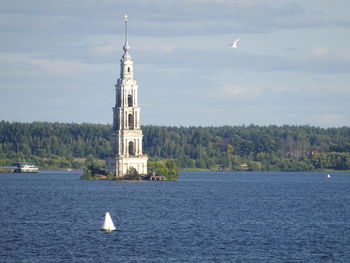 View of lighthouse by sea against sky