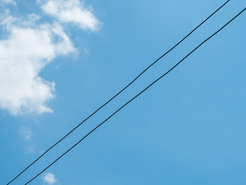 Low angle view of power lines against blue sky