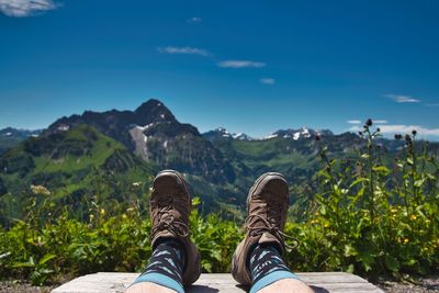 Low section of man on mountain against sky