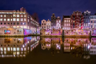 Graffiti on buildings by canal at night