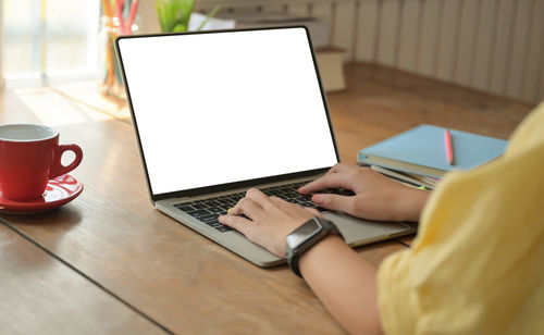 Midsection of man using mobile phone on table