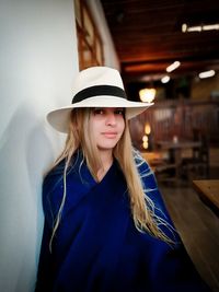 Portrait of smiling woman wearing hat while sitting in restaurant