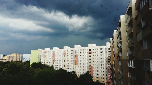 Buildings in city against storm clouds