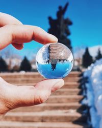 Midsection of person holding crystal ball against statue at temple