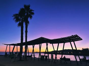 Silhouette palm trees on beach against clear sky at sunset