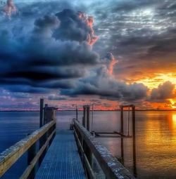 Pier on sea against cloudy sky