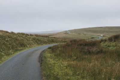 Road amidst field against clear sky