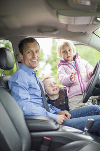 Portrait of happy father with children in car