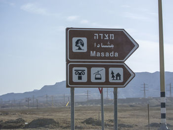 Information sign on road against sky masada