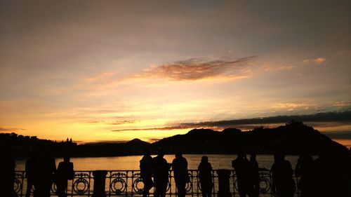 Silhouette people standing against sea during sunset