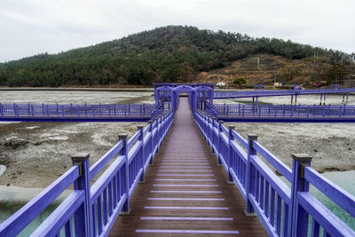 People walking on pier over sea against sky