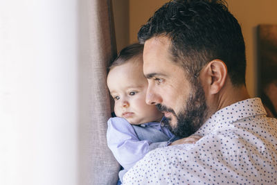 Close-up of man with son by window at home