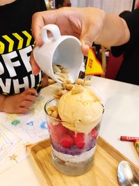 Close-up of hand holding ice cream on table