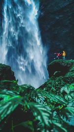 People standing by waterfall