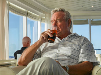 Young man drinking glass while sitting outdoors