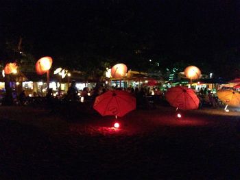 People in illuminated city against sky at night