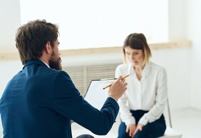 Businesswoman using digital tablet while standing against wall