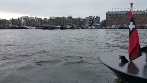 Boats moored in river with city in background