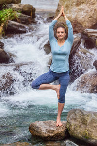 Full length of woman exercising standing on rock