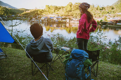 Rear view of friends sitting by lake