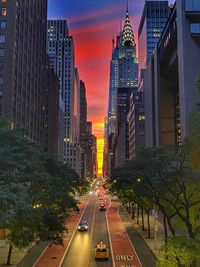 Illuminated city street amidst buildings against sky