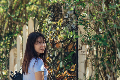 Portrait of young woman standing against plants