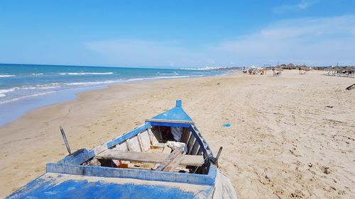 Deck chairs on beach against sky