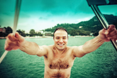 Portrait of happy shirtless man against sea