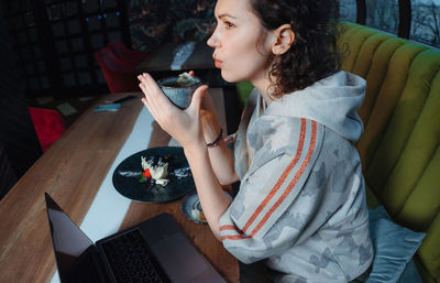 Young woman using mobile phone while sitting on table