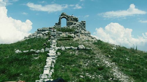 Ruins of building on hill against cloudy sky