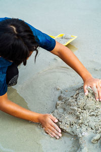 High angle view of boy playing in sand on seashore