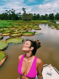 Portrait of young woman standing by lake amd victoria water lily