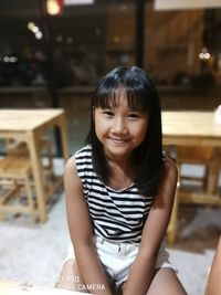 Portrait of smiling girl sitting on table in restaurant
