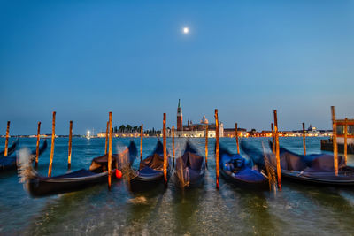 Boats moored in canal against clear blue sky