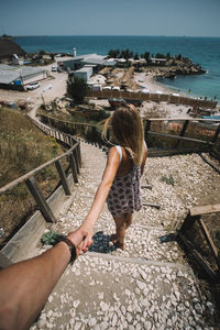 Cropped image of man holding woman hand on steps during summer