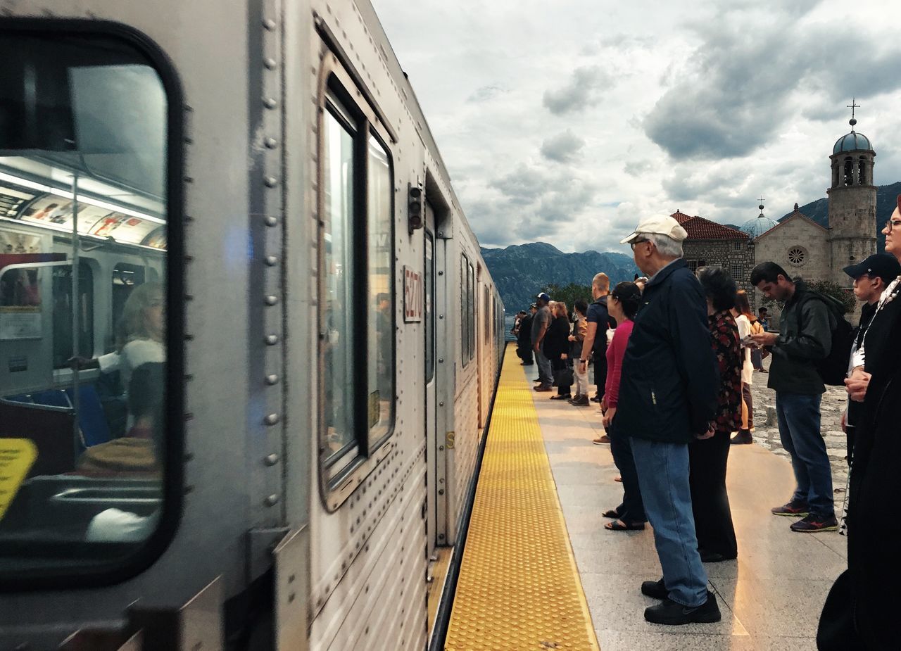 train - vehicle, rear view, transportation, cloud - sky, sky, people, public transportation, subway train, large group of people, adults only, only men, adult, men, warm clothing, outdoors, day