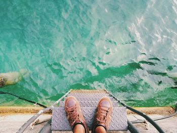 Low section of man standing on steps over sea