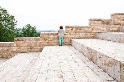 Rear view of woman standing on steps against clear sky