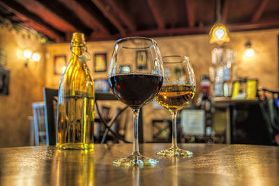 Wineglasses and bottle on table in illuminated cafe