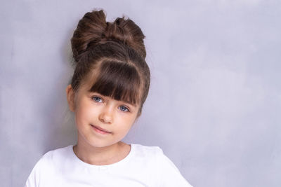 Portrait of young woman standing against wall