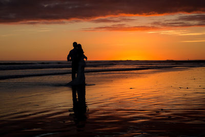 Silhouette of people on beach at sunset