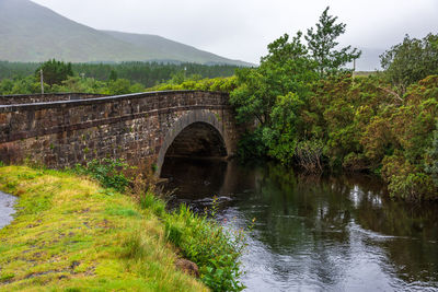 Arch bridge over river against sky