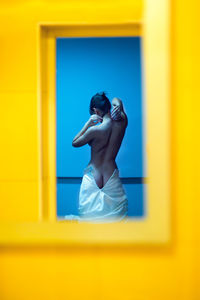 Reflection of shirtless woman in mirror at home