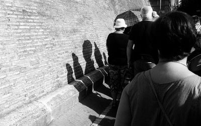 Rear view of people walking by wall