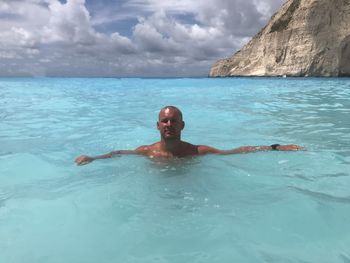 Portrait of shirtless man swimming in sea