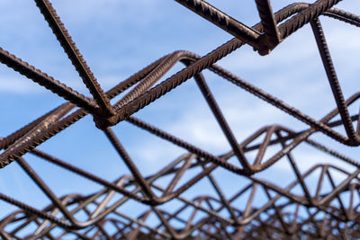 Low angle view of rusty metal fence against sky