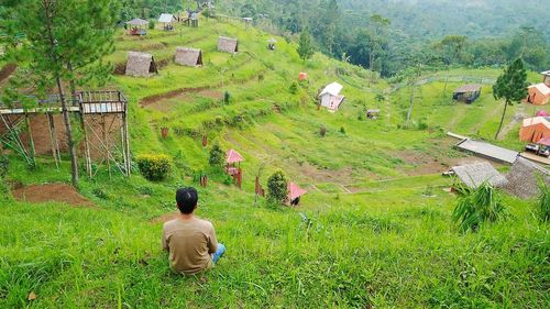 Rear view of man sitting on hill in village