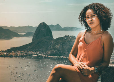 Young woman looking at sea against mountains