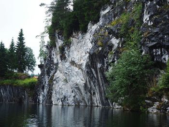 Scenic view of rocks by trees against sky