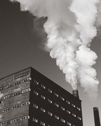 Low angle view of smoke emitting from chimney against sky